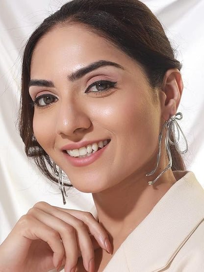 Model wearing exaggerated bow earrings with elegant makeup and white outfit