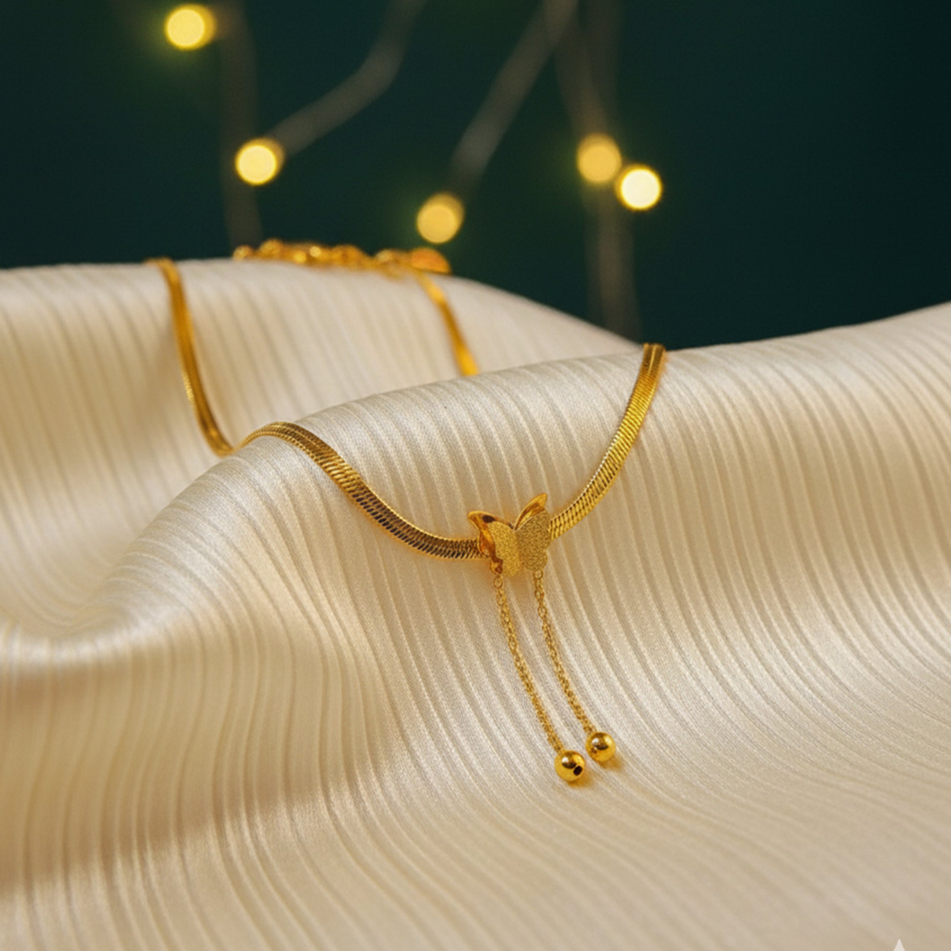 Elegant Snake Chain Butterfly Necklace draped on silky fabric with bokeh lights.