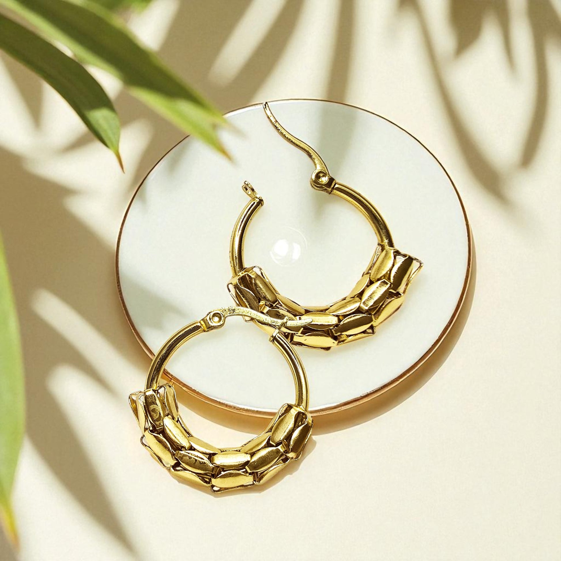 Snake Scale Earrings – close-up gold hoops with snake-scale detailing on flat lay