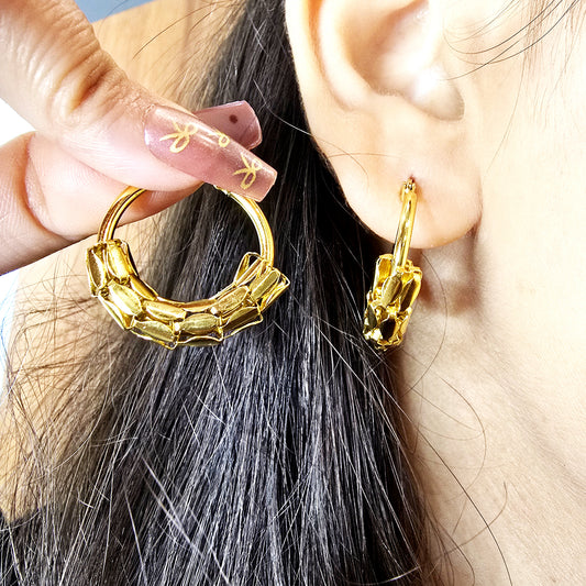Snake Scale Earrings- Gold hoop earrings being worn and held up to the ear.