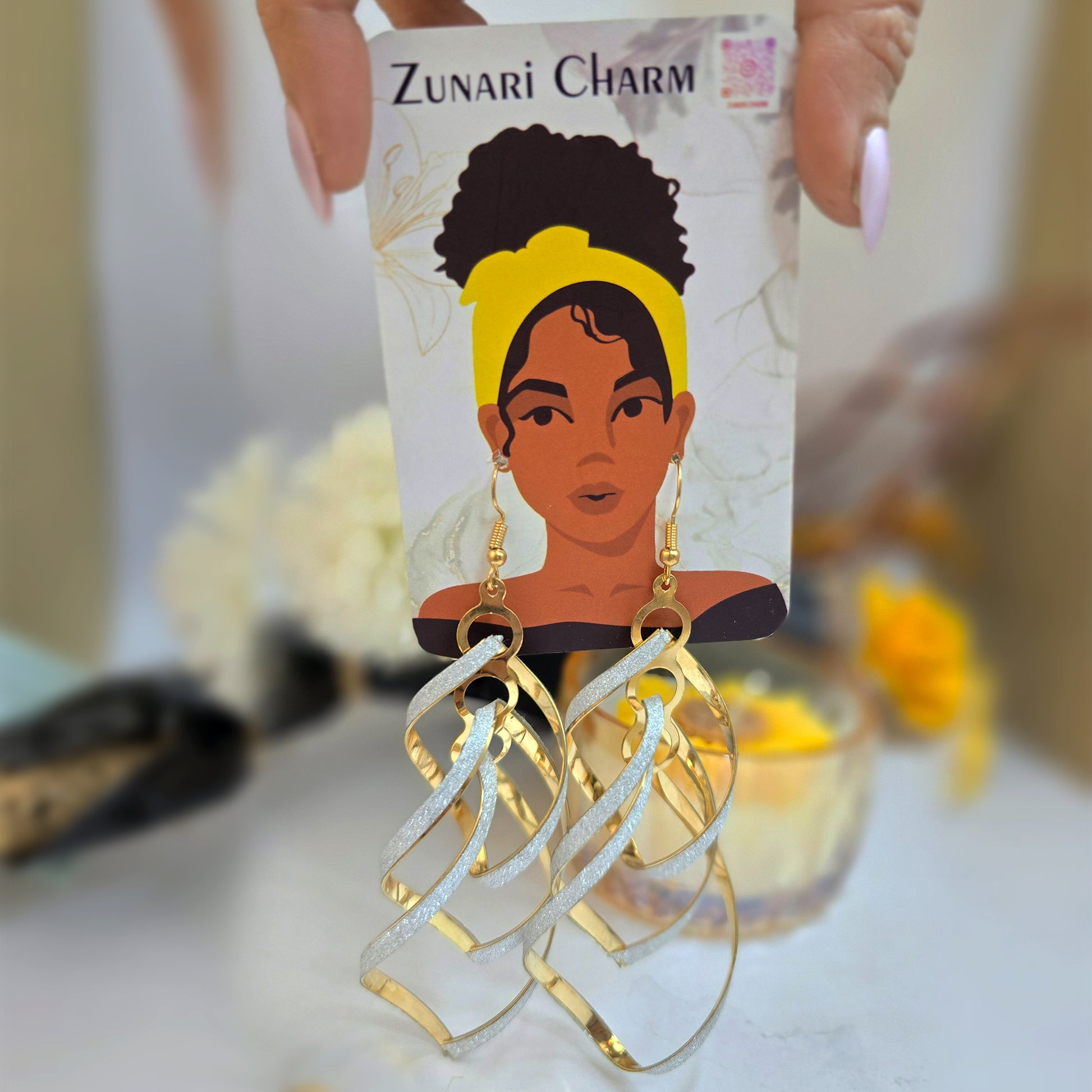 Large sparkling tassle earrings displayed on a Zunari Charm branded card with the signature woman illustration.