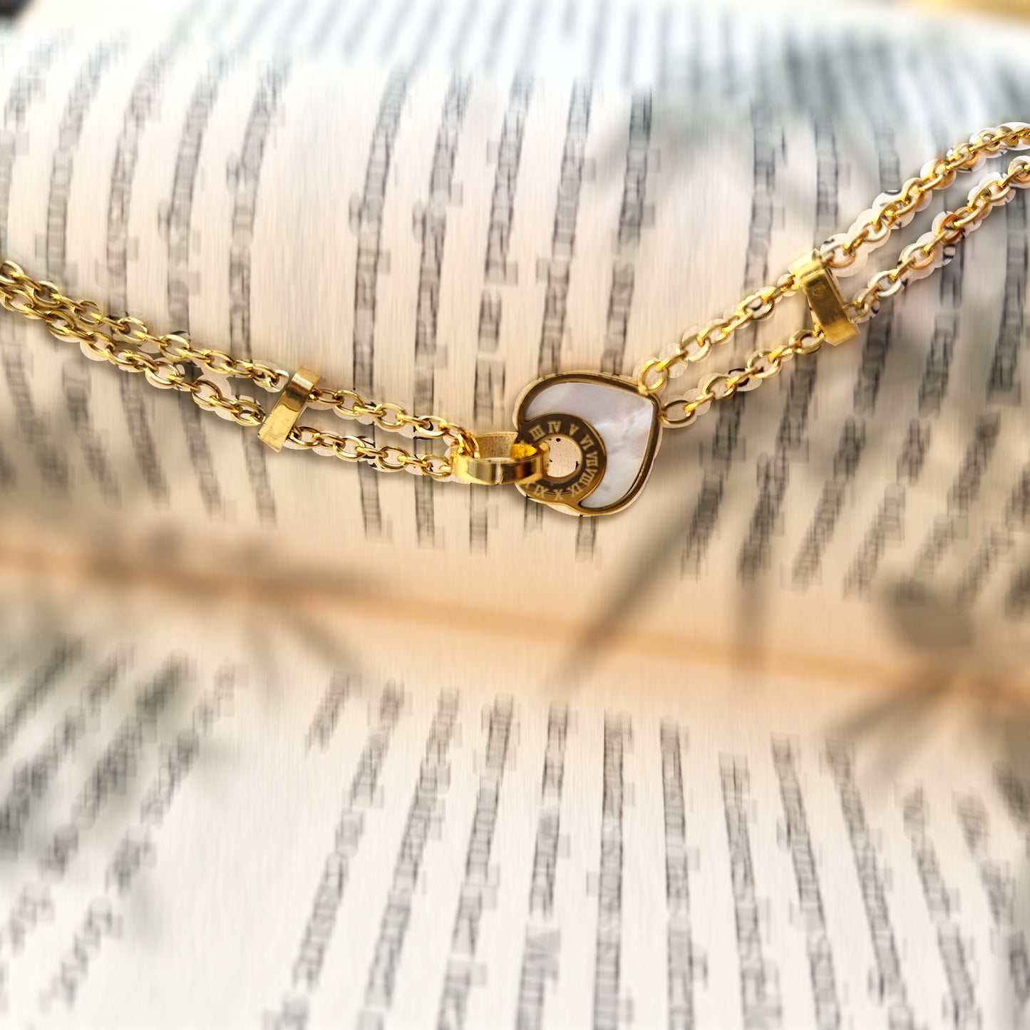 Dainty gold station bracelet with small beads resting on open book pages.