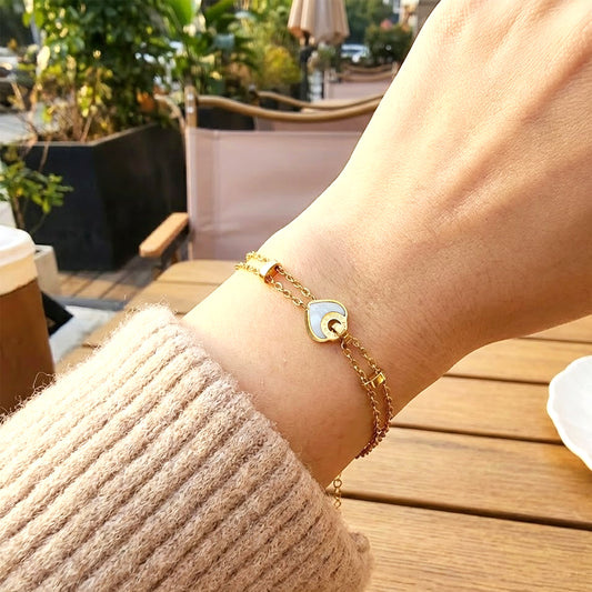 Woman’s wrist wearing a minimalist gold beaded chain bracelet.