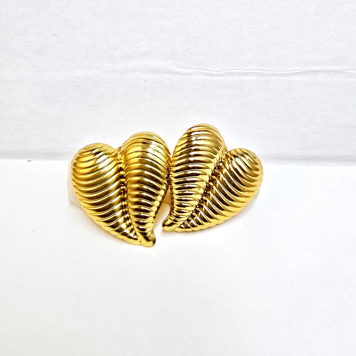 A pair of gold-plated striped heart stud earrings with a horizontal ribbed texture on a white background.