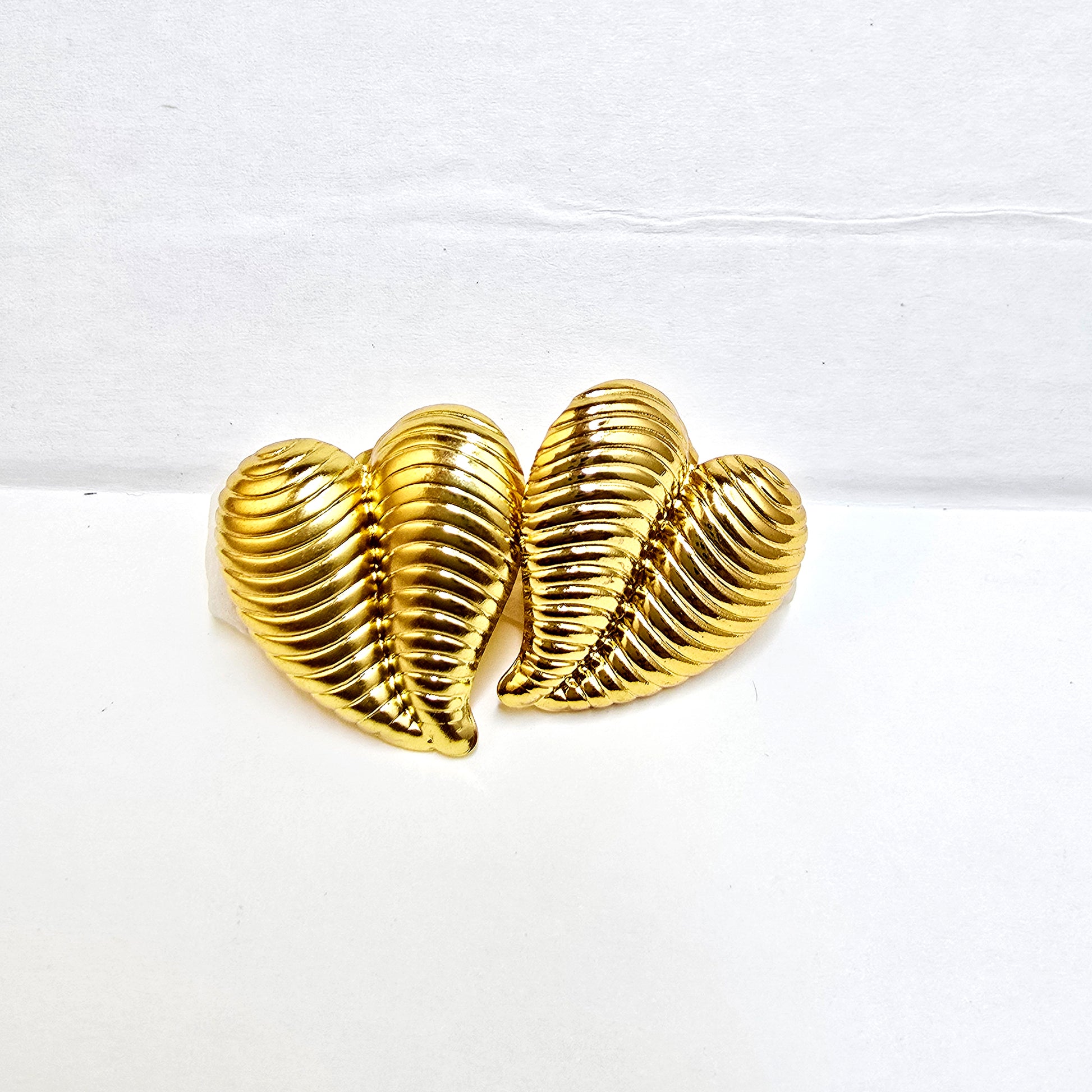 A pair of gold-plated striped heart stud earrings with a horizontal ribbed texture on a white background.