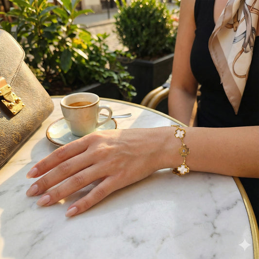 Woman wearing radiant white and gold clover bracelet at a cafe with designer accessories.
