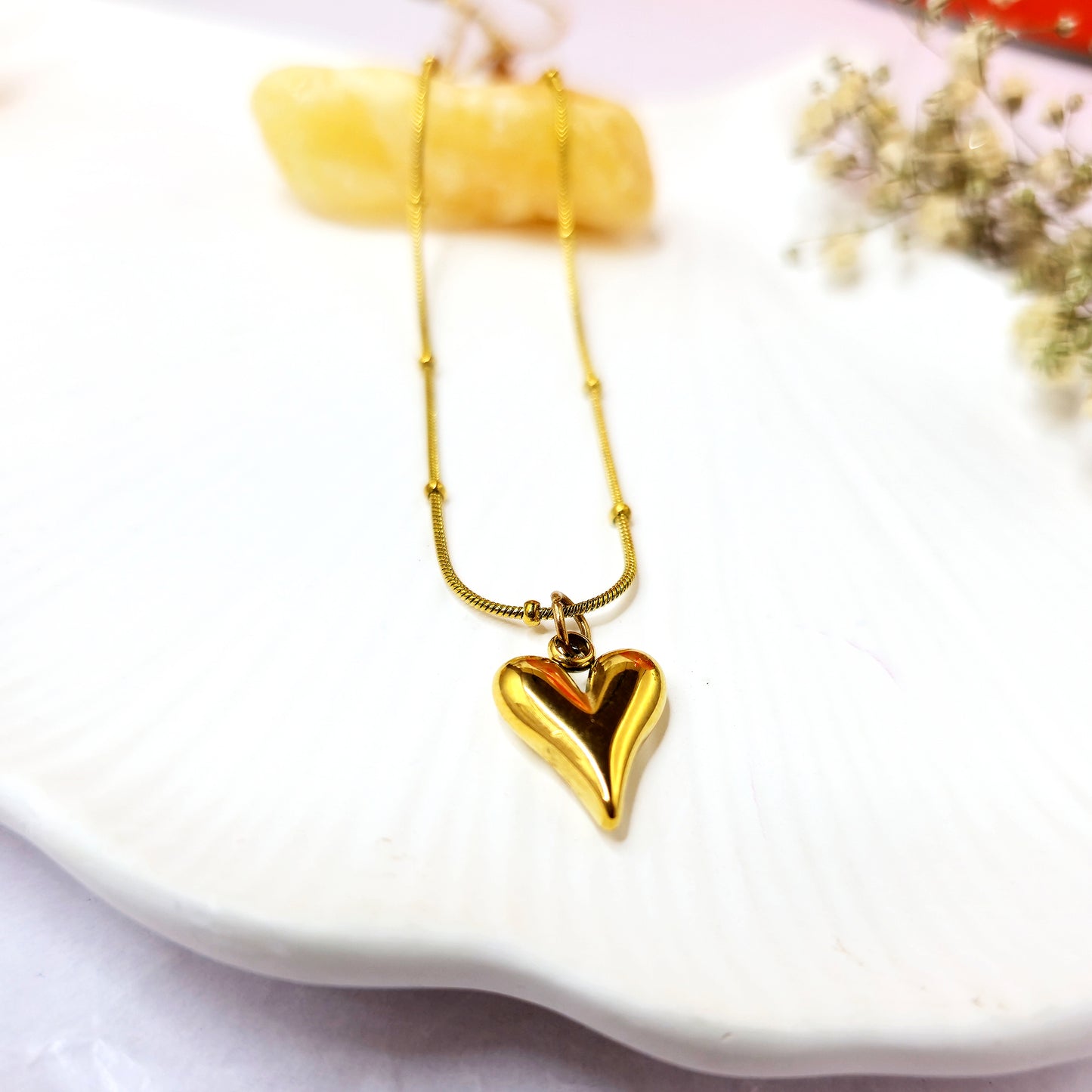 Flatlay of TearDrop Heart Pendant Chain on shell plate – gold minimalist necklace