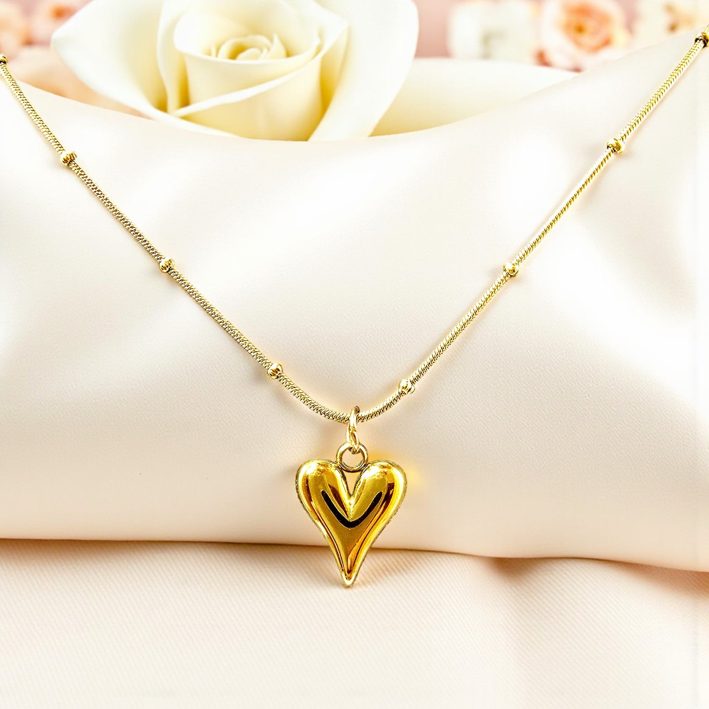 Close-up of TearDrop Heart Necklace on satin cushion – gold shine and detail