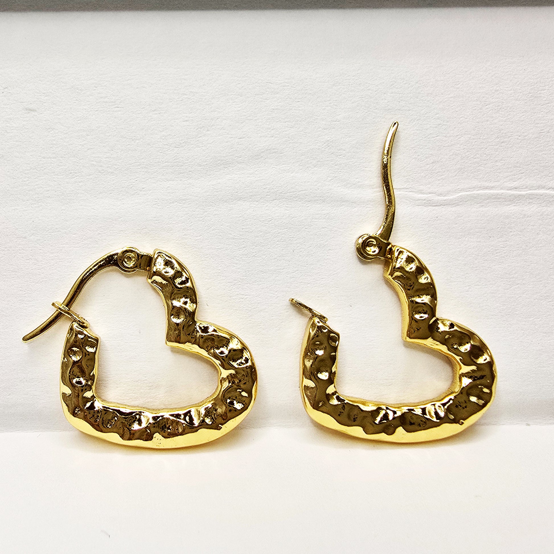 Pair of gold textured heart hoop earrings displayed flat on a white background.