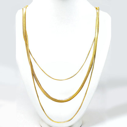 Trinity Layers Necklace displayed on a white bust stand – gold layered chains.