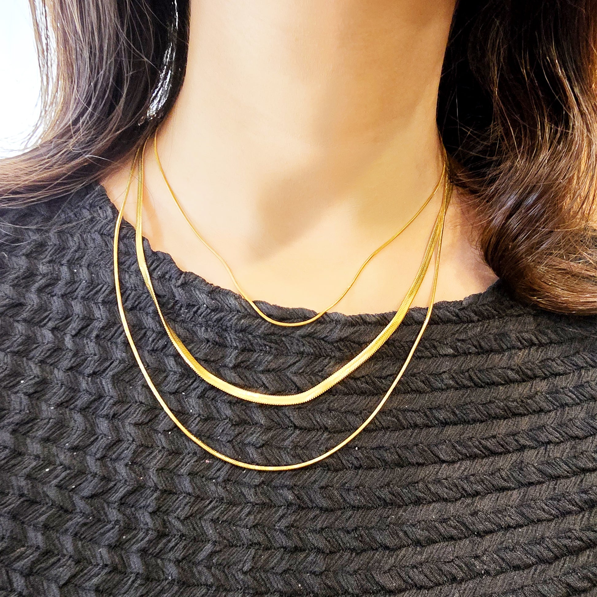 Woman wearing Trinity Layers Necklace – gold-toned layered snake chain jewelry.