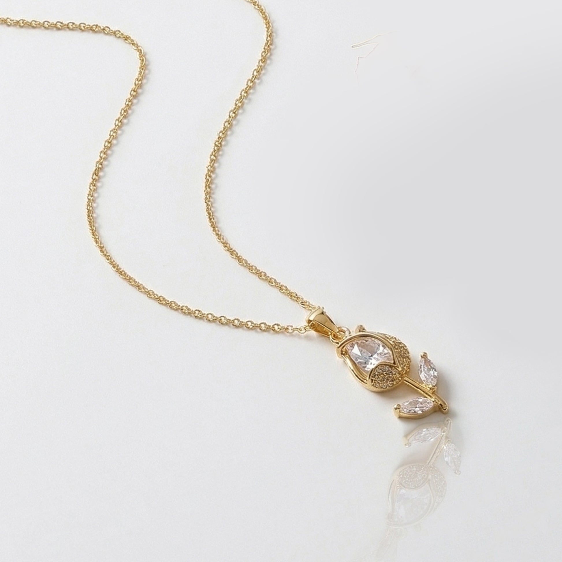 Gold tulip pendant necklace with crystal stones on white background minimalist jewelry product shot