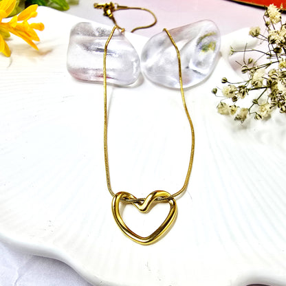 Gold-plated minimalist twisted open heart pendant necklace on a white display.