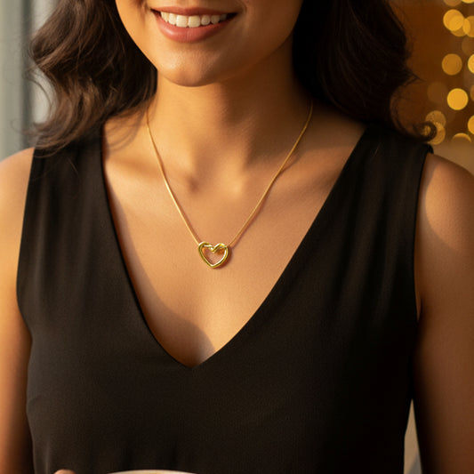 Model wearing the dainty gold twisted heart necklace against a black V-neck top, showing the drop length.