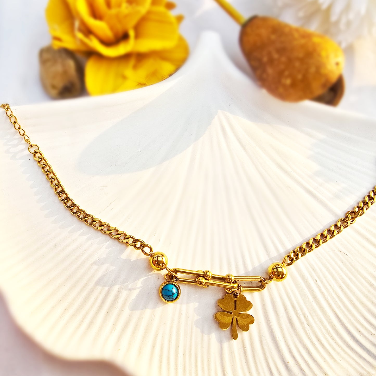 High-angle flat lay of the gold hardware bracelet on a decorative white shell tray.