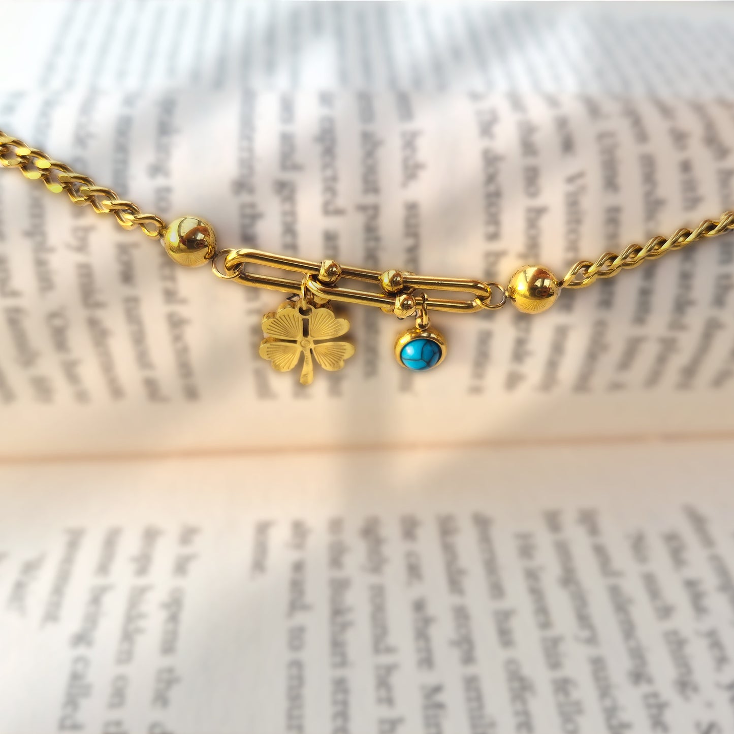Aesthetic close-up of the U-shaped hardware and black clover charm resting on a book page.