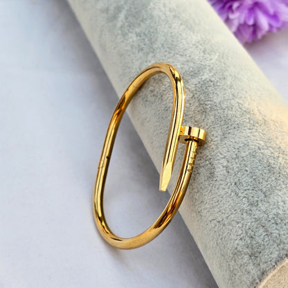 Side view of hinged gold nail bracelet showing sleek polished finish.
