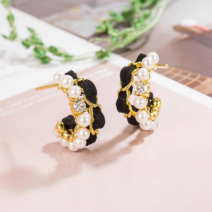 Velvet and pearl gold hoop earrings placed on a pastel background