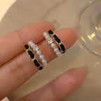 Black velvet earrings with pearl strands and crystal stones held delicately