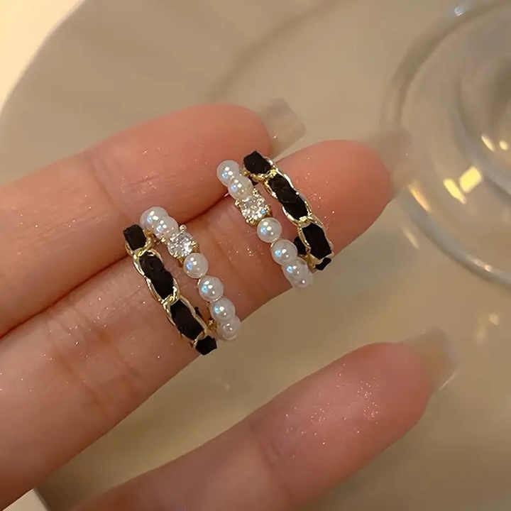 Black velvet earrings with pearl strands and crystal stones held delicately