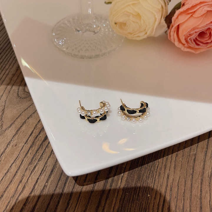 Pearl and gold-accent black velvet earrings styled with wine glass and roses
