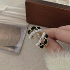 Model holding black velvet pearl earrings with rhinestone detailing