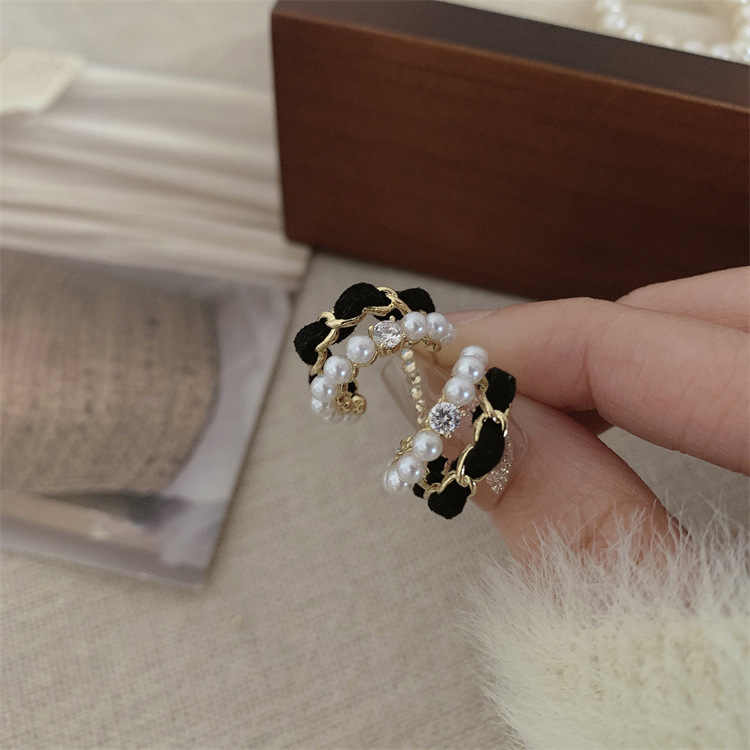 Model holding black velvet pearl earrings with rhinestone detailing