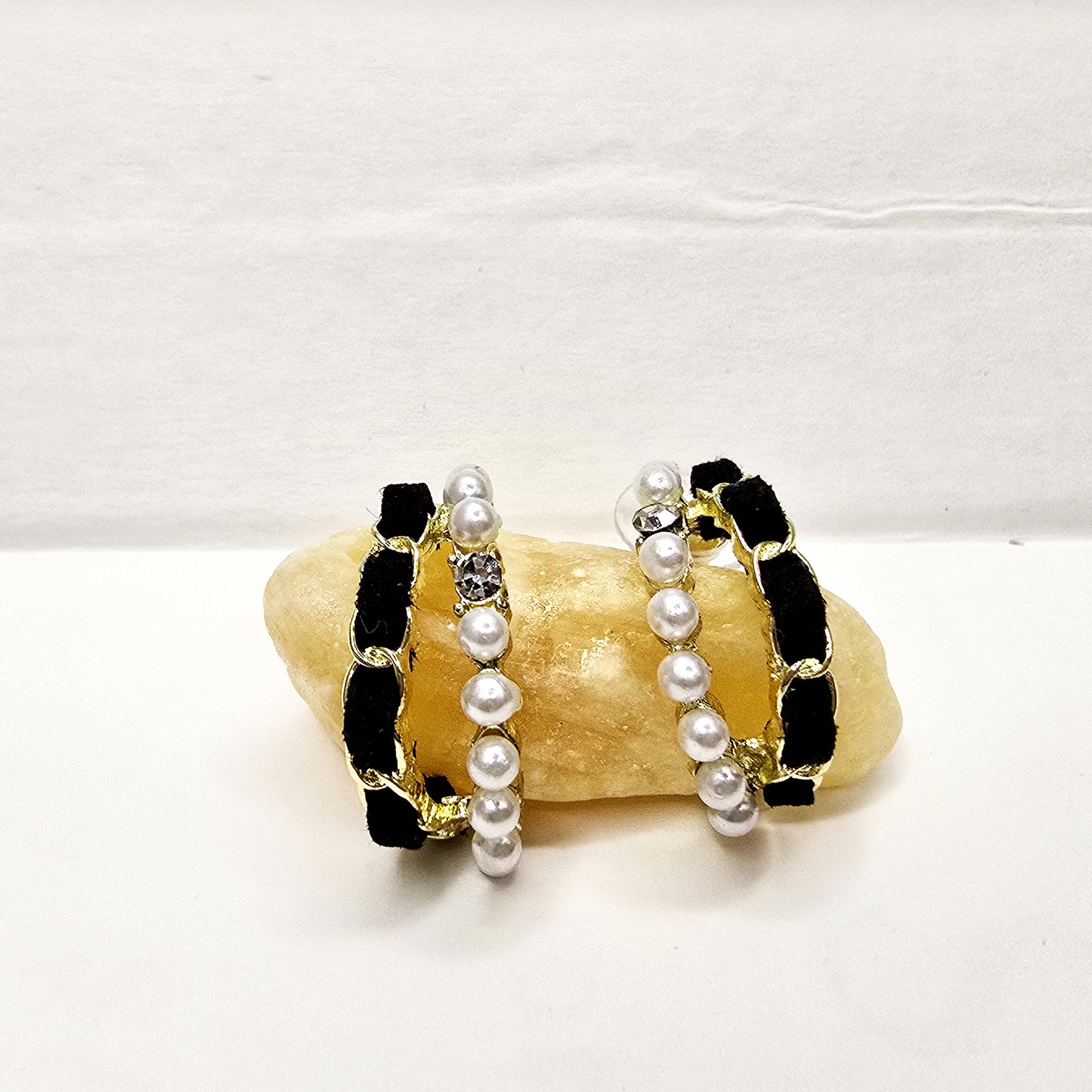 Velvet Pearl Earrings displayed on white surface with textured stone