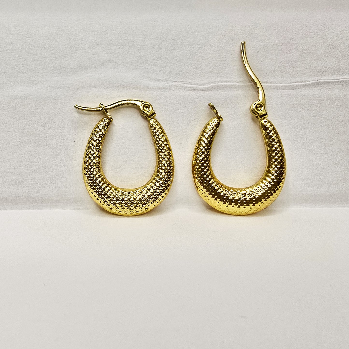 Close-up of vintage crescent gold hoop earrings with textured finish