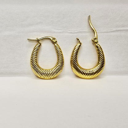 Close-up of vintage crescent gold hoop earrings with textured finish