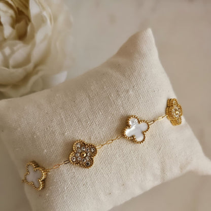 Minimalist white clover bracelet placed on cushion with floral background