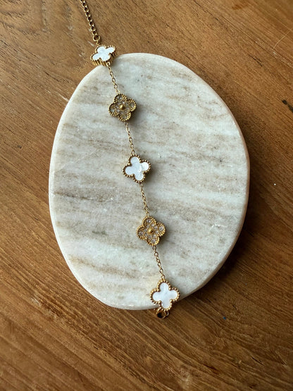Gold and white clover bracelet displayed on a marble slab