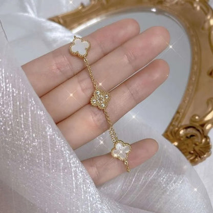 Close-up of clover bracelet held in hand with sparkly background