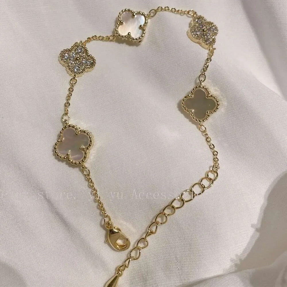 Gold bracelet with clover charms shown on white satin fabric
