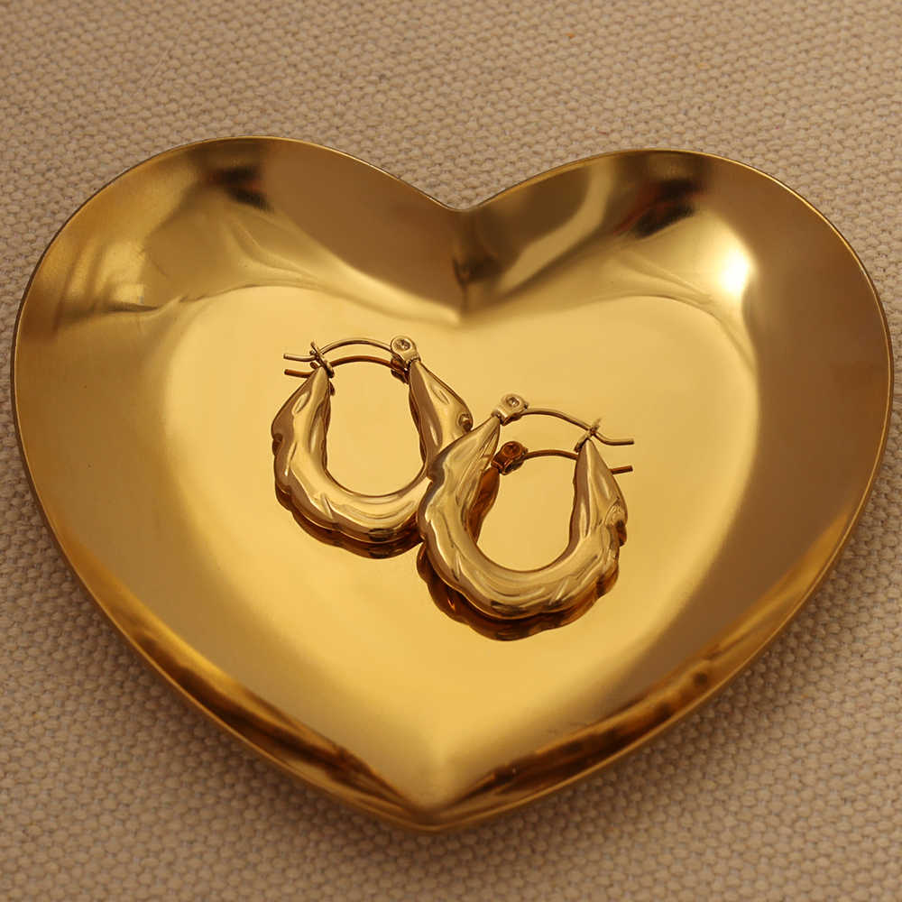 Pair of zigzag hoop earrings displayed in a heart-shaped golden dish on a beige fabric background.
