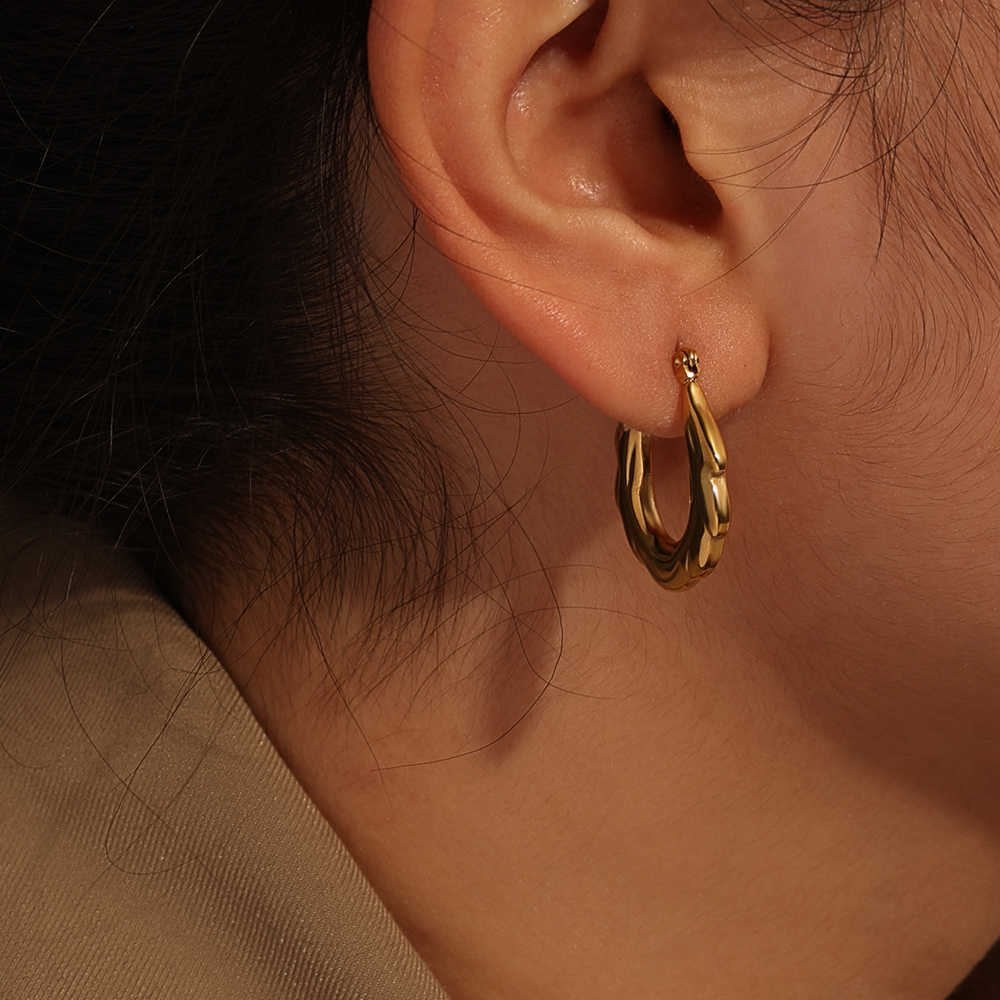 Model wearing a single gold zigzag hoop earring, highlighting the elegant contour against the ear.