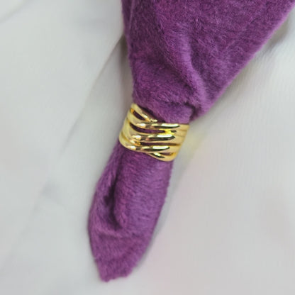 A 360-degree rotating video of the Ripple Band Ring, a gold-toned layered statement ring with wave-like ripples, displayed on a purple velvet background for an elegant showcase.