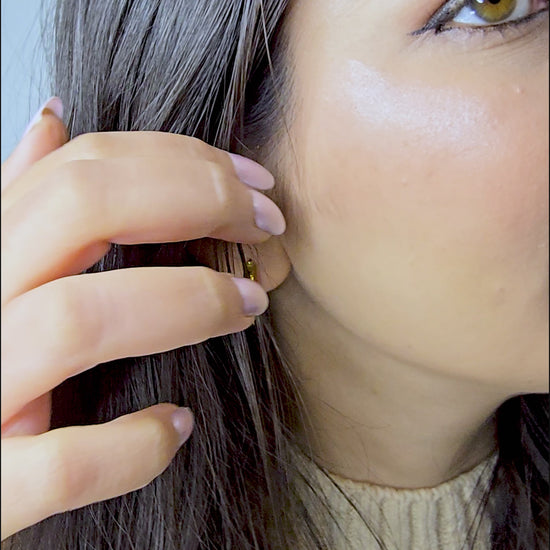 Video demonstration showing the shine, lightweight movement, and secure fit of the gold Crest hoop earrings on a model.