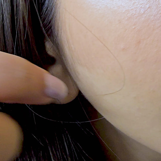 A detailed view of the model wearing only the Etched Heart studs from the 3-in-1 set. The camera focuses on the intricate, wavy etched pattern on the heart's surface, demonstrating its use as a sophisticated, everyday minimalist accessory.