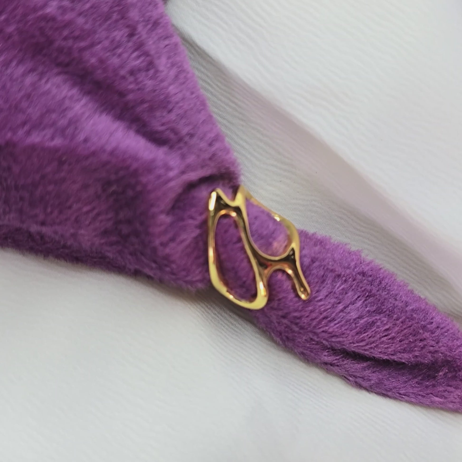 360-degree video of Abstract Frame Ring in gold, rotating on a table. Modern open-frame design displayed on a purple textured cloth with a white background.