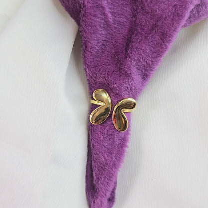 60-degree video of a gold Molten Drop Ring displayed on a rotating table, with the ring placed against a purple velvet and white fabric backdrop, highlighting its modern fluid design and reflective shine.