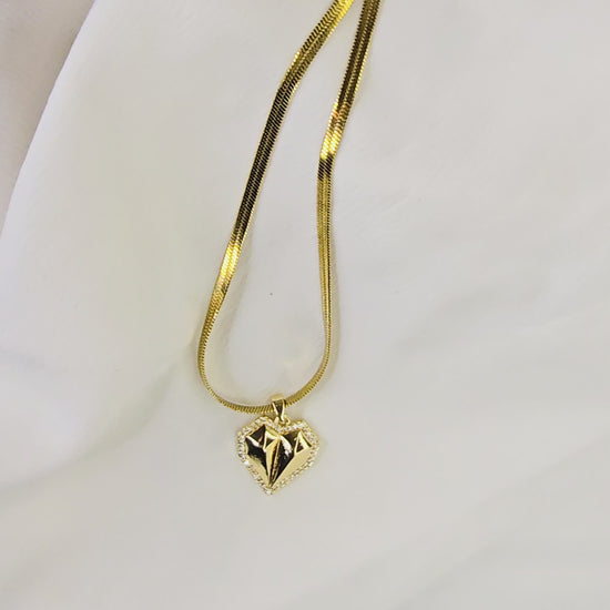 Video showing the 3D form, faceted surface, and movement of the gold-plated geometric heart pendant on a herringbone chain.