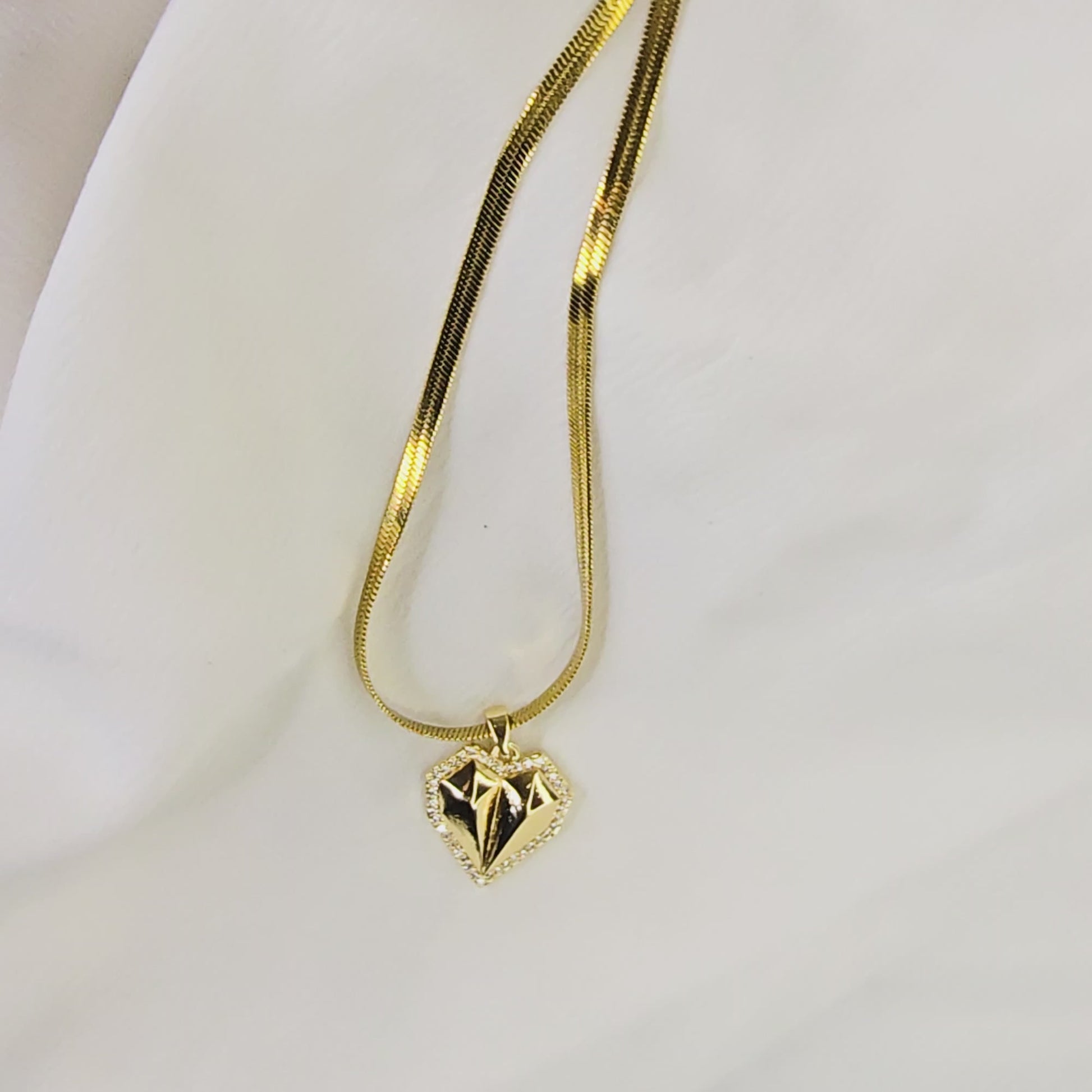 Video showing the 3D form, faceted surface, and movement of the gold-plated geometric heart pendant on a herringbone chain.