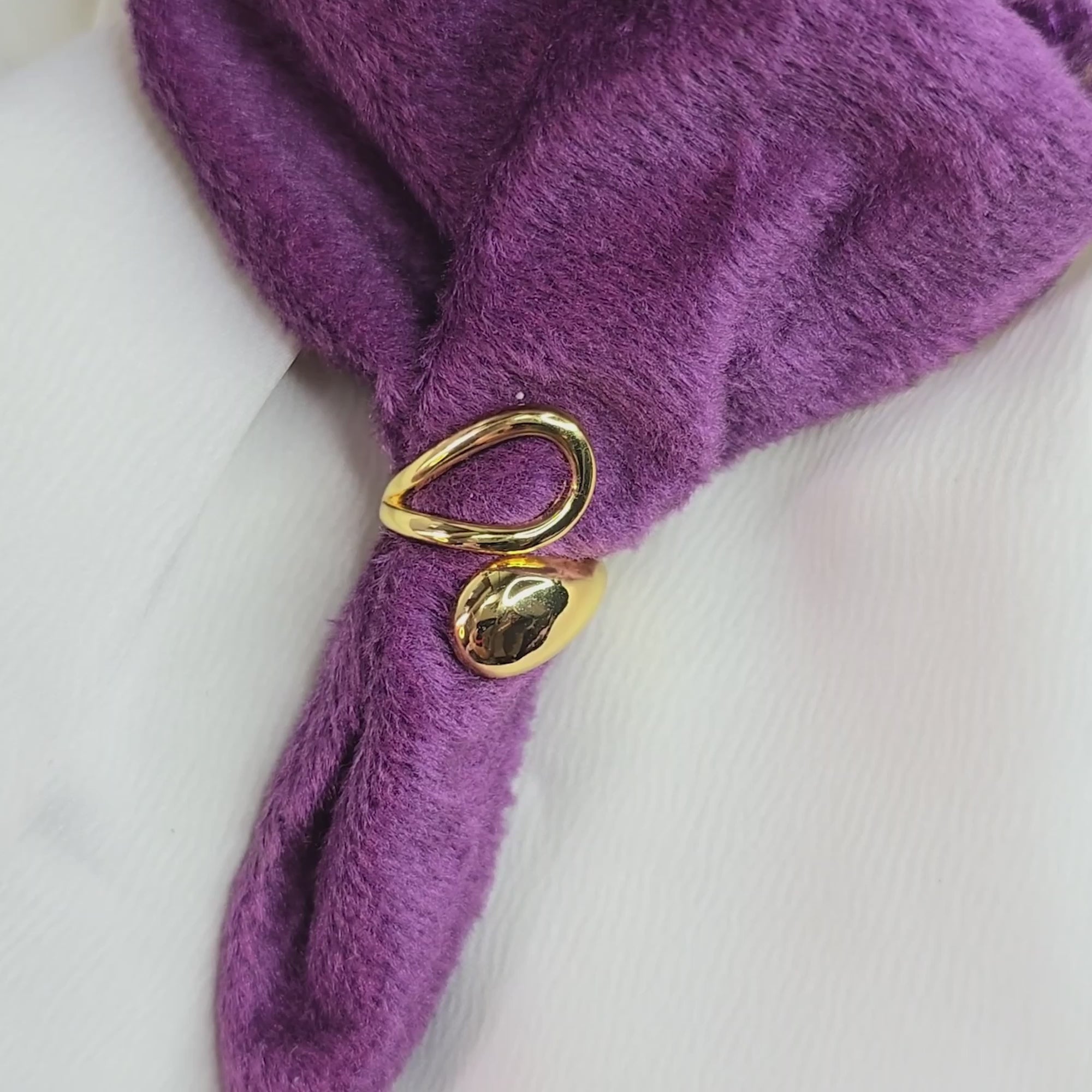 360-degree rotating video of gold molten drop ring with fluid abstract design, displayed on purple velvet and white fabric background, elegant jewelry showcase.