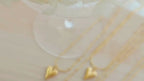 Close-up video of a gold-toned water drop heart pendant necklace with beaded chain, showcased in elegant lighting to highlight its shine and minimalist design