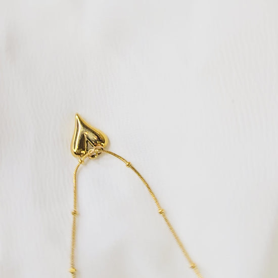 360-degree video of TearDrop Heart Pendant Chain on white background, showing gold-toned beaded chain with teardrop heart pendant and reflective shine