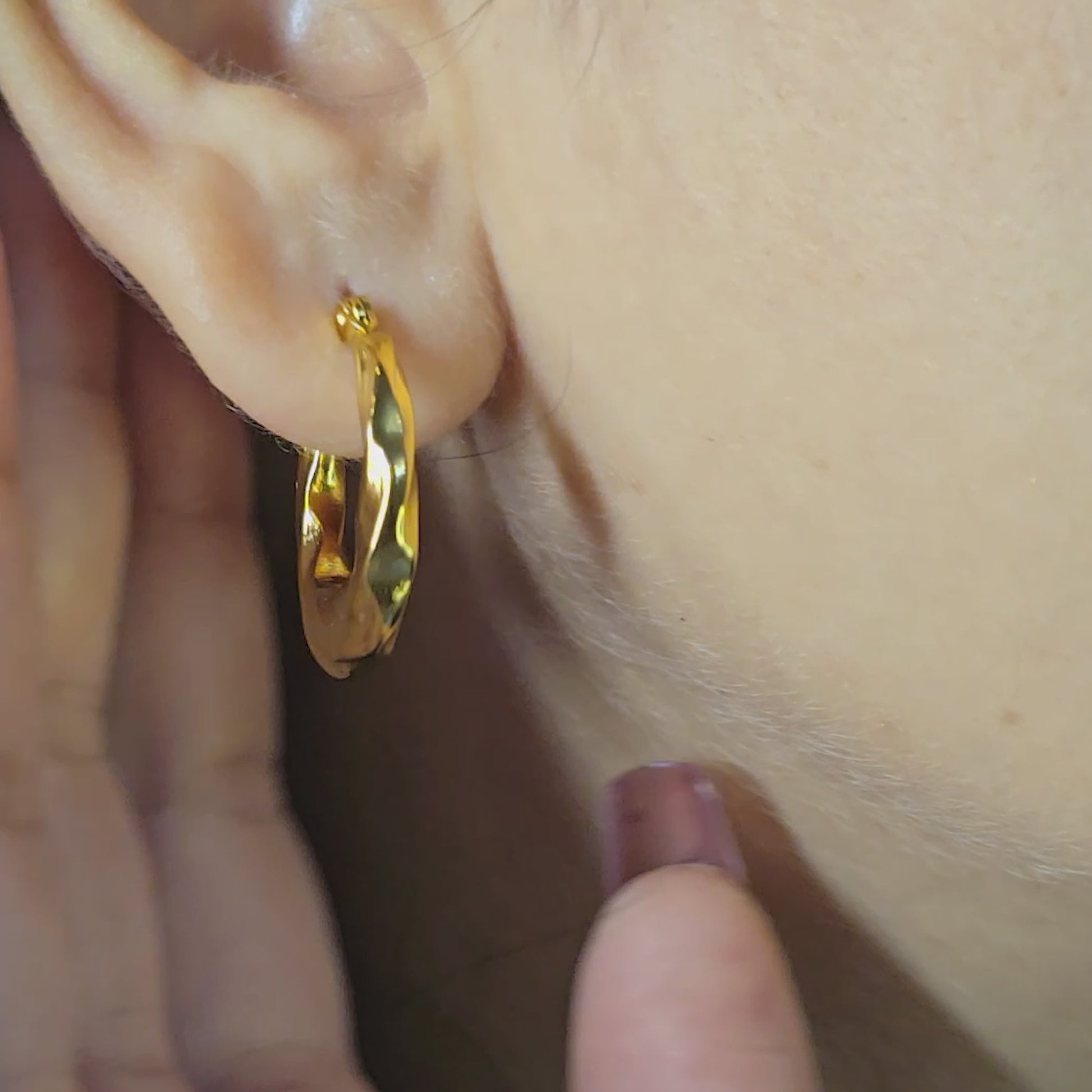 Model wearing Curly Twist Earrings—gold-toned textured hoop with twisted design, close-up view.