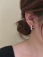 Close-up video of a woman elegantly showcasing black velvet pearl hoop earrings on her ear, highlighting the pearl, gold, and velvet detailing.