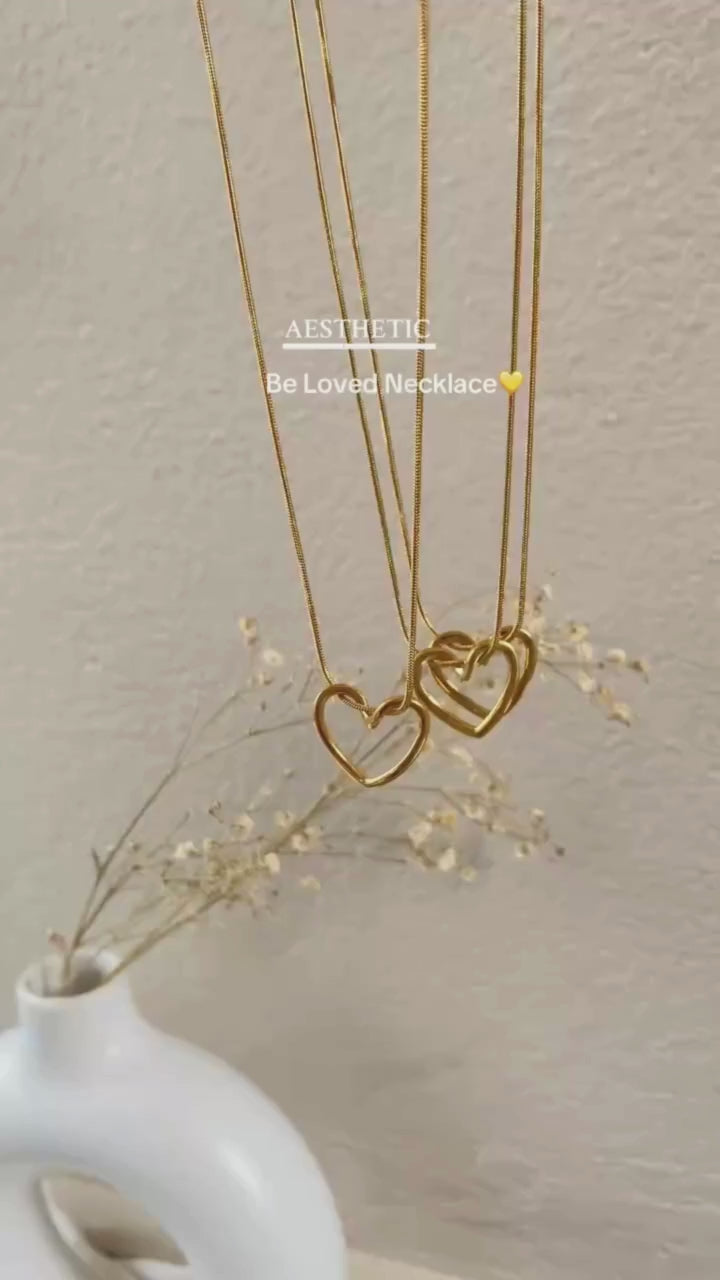 Video showcasing the Twisted Heart Necklace in motion — close-up views of the gold-toned sculpted heart pendant, snake chain shine, and adjustable clasp detail on a neutral background