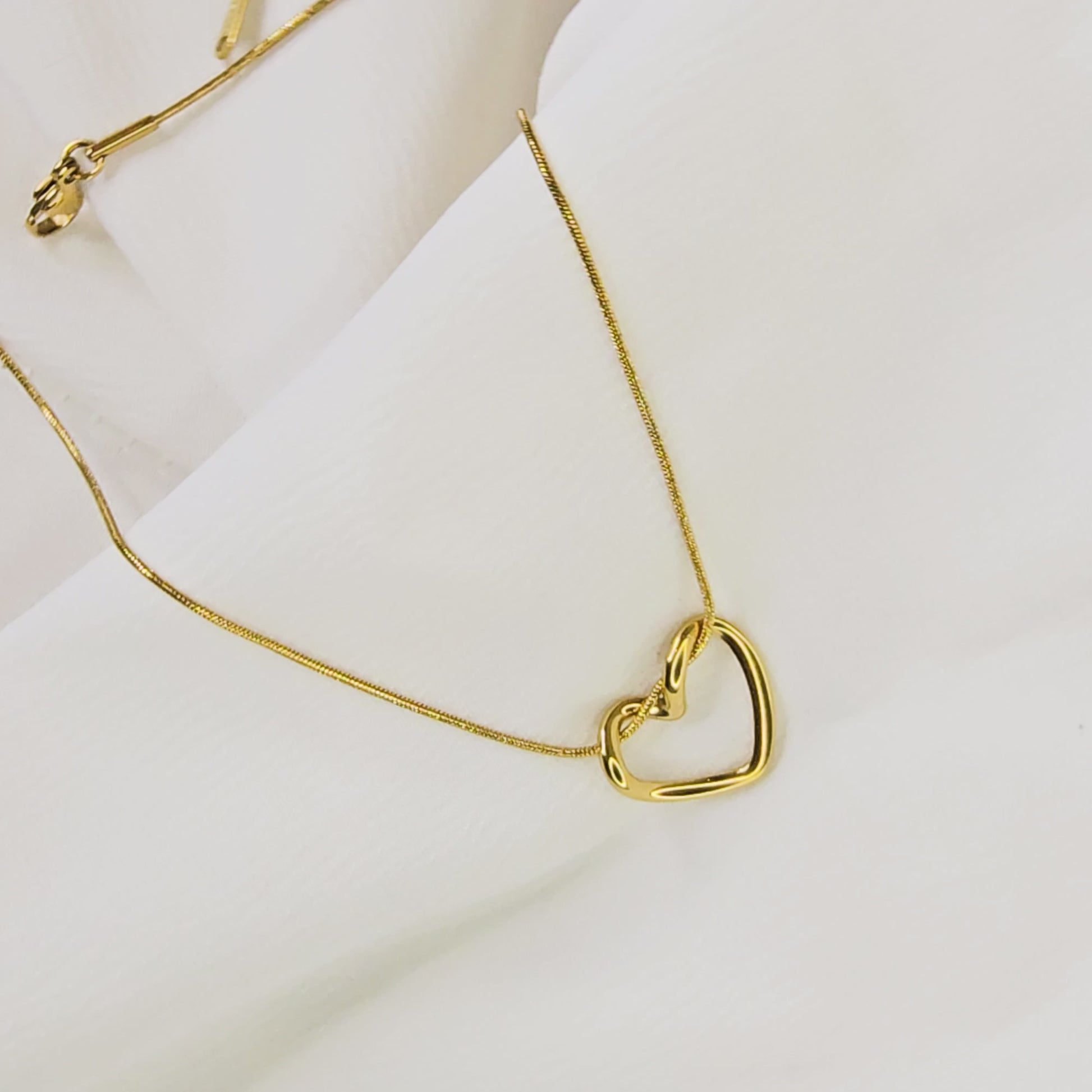 Video showing the smooth, three-dimensional curvature of the gold-plated twisted heart pendant.